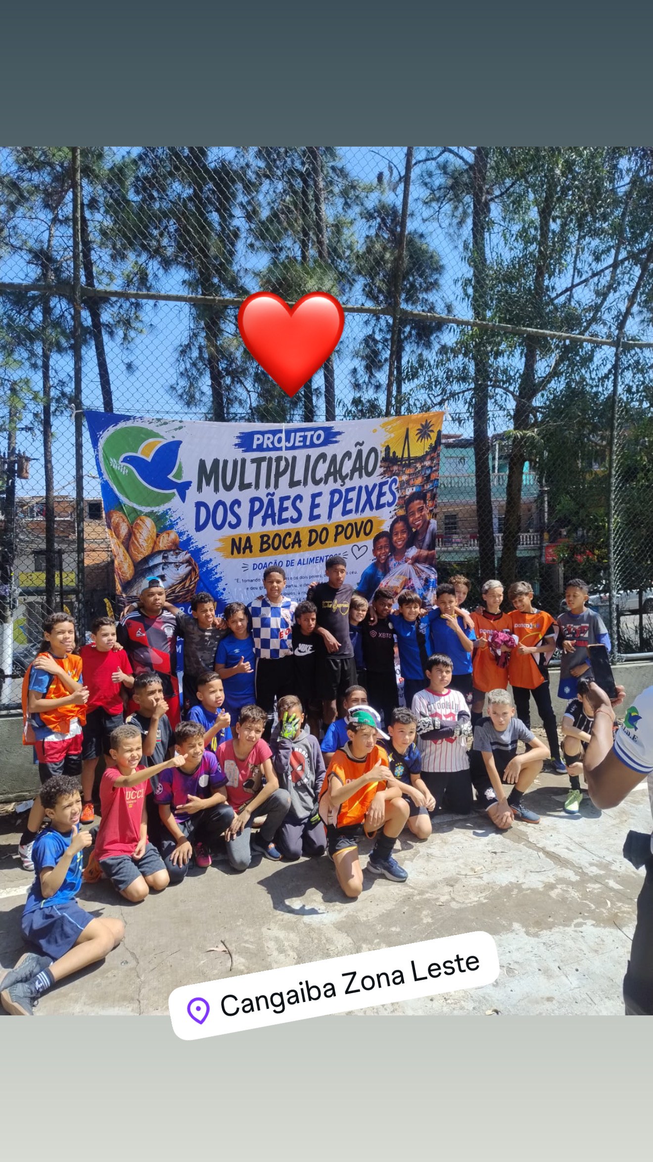 Grupo de crianças e jovens reunidos em uma quadra diante do banner do Projeto Multiplicação dos Pães e Peixes Na Boca do Povo